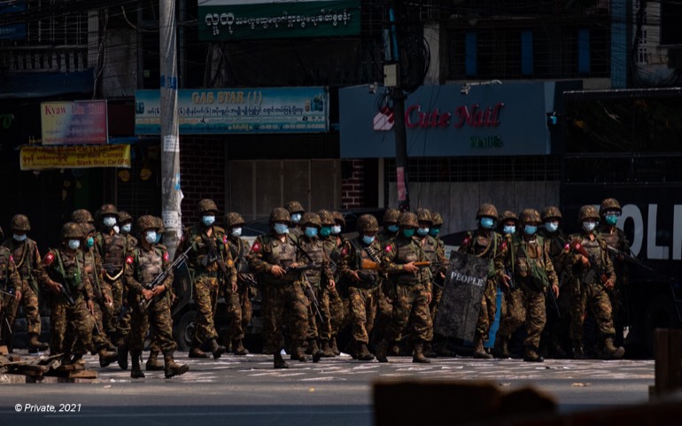 Soldiers in helmets and masks advancing along a city street in Myanmar