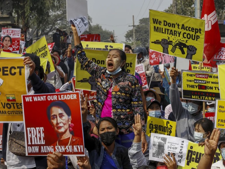 Protesters in Myanmar raising signs reading "We don't accept military coup" and "Free Daw Aung San Suu Kyi"