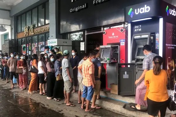 A long queue of people waiting to withdraw cash at bank ATMs on a street in Myanmar